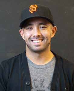 A photo of a smiling Asian man with a San Francisco Giants hat on.